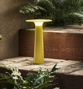 Yellow outdoor lamp on a stone ledge with plants around