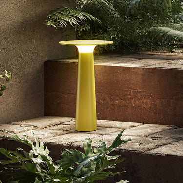 Yellow outdoor lamp on a stone ledge with plants around