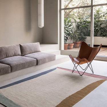 Modern living room with a gray sofa, brown chair, and large window.