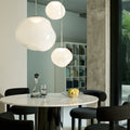 Modern Tom dixon dining area with round table, chairs, and pendant lights.