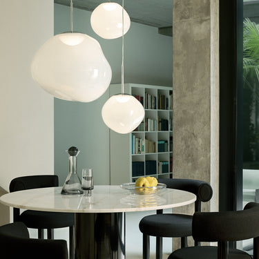 Modern Tom dixon dining area with round table, chairs, and pendant lights.