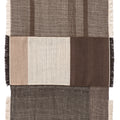 Textured dhurrie rug with a patchwork design featuring shades of brown and black on a white background.