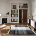 Living room with a fireplace, prouvé kangaroo armchair, and decorative frames on the wall.