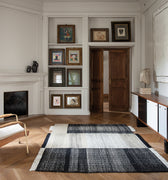 Living room with a fireplace, prouvé kangaroo armchair, and decorative frames on the wall.