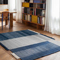 blue woven rug with charlotte perriand bookcase in a dining room