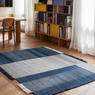 blue woven rug with charlotte perriand bookcase in a dining room
