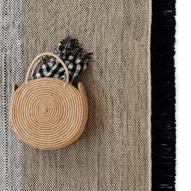 Round woven basket with a checkered bag on a textured surface