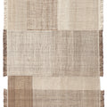 Textured jute and wool area rug with a patchwork design and fringe n neutral colors on a white background