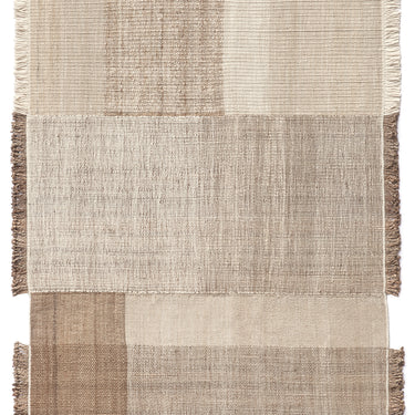 Textured jute and wool area rug with a patchwork design and fringe n neutral colors on a white background