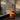 Orange cylindrical table with a pendant light against a concrete wall.