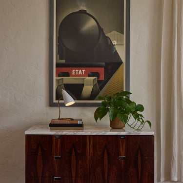 Vintage ostuni table lamp on knoll credenza with plant and lamp, framed poster on the wall