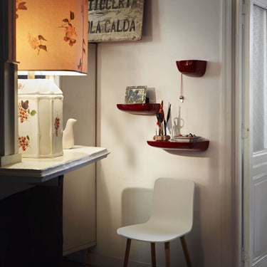 Small room with a desk, chair, and decorative items on a wall shelf.