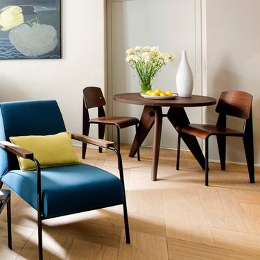 gueridon table in walnut with two standard chairs in a hotel room with a soft blue prouve armchair