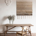 Wooden dining table with a chair in a room with a textured wall and decorative elements.