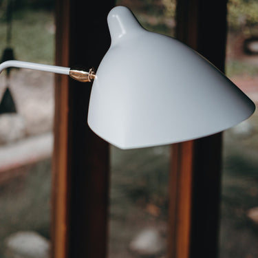 White lamp with a curved arm against a blurred outdoor background