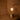 muse brass portable light with a lit bulb hanging against a wooden wall.