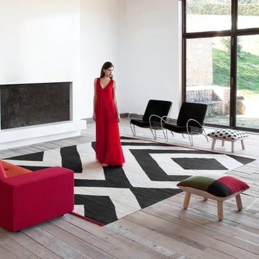 Modern living room with a red sofa, black and white rug, and a woman in a red dress.